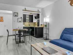 een woonkamer met een blauwe bank en een tafel bij Escapade Azuréenne Idéale à Saint Laurent in Saint-Laurent-du-Var