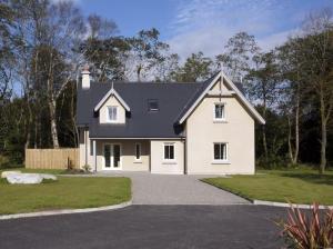 a white house with a black roof and a driveway at Dunkerron Woods 3 bedroom 4022 in Kenmare +6 photos