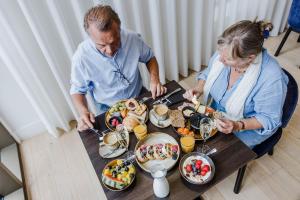 Ein Mann und eine Frau sitzen an einem Tisch mit Essen in der Unterkunft Corsendonk Turnova in Turnhout