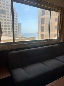un divano seduto di fronte a una grande finestra di Rawche 30 Apartments a Beirut