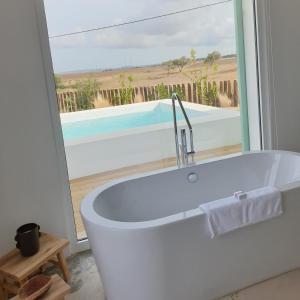baño con bañera blanca y ventana en Casa Calmar, en Porto Covo