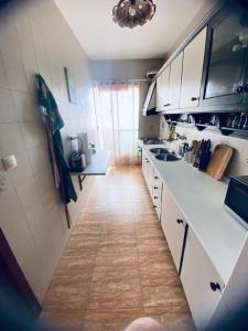 a kitchen with white cabinets and a wooden floor at Completa y Amplia Habitación a 10 minutos de la playa Casa Compartida in Algaida