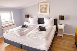 a large white bed in a room with two lamps at CBlue "Apartmenthaus Chrischanshof" in Warnemünde