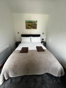 a bedroom with a large white bed with two towels on it at Small home in Llanfairpwll in Llanfairpwllgwyngyll