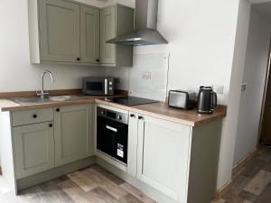 a kitchen with white cabinets and a stove top oven at Small home in Llanfairpwll in Llanfairpwllgwyngyll