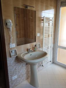 ein Bad mit einem Waschbecken, einem Spiegel und einem Fenster in der Unterkunft A Due Passi Dal Molino in Valderice