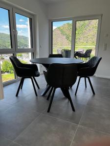 Ferienwohnung Weitblick في كوشيم: غرفة طعام بها طاولة وكراسي ونوافذ