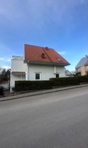 a white house with a red roof next to a street at Superhomes 1 gäst in Gothenburg