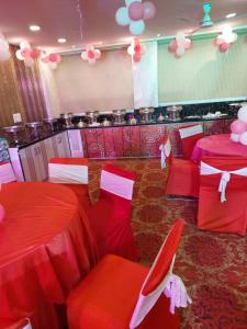 una stanza con tavoli e sedie rossi e palloncini di The Noble Suites, Near Spectrum Mall a Noida
