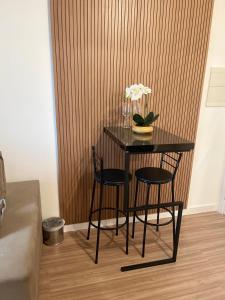 un tavolo nero con due sedie e un vaso di fiori di Flat de Luxo Aeroporto Congonhas - Hotel eSuites a San Paolo