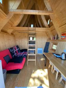 a living room of a tiny house with a red couch and a table at Domaine des Hayes in Maxent