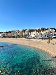 a beach with blue water and buildings in the background at Antiquari de Blanes Apartamento Boutique en la Costa Brava in Blanes