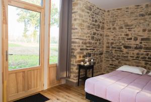 a bedroom with a brick wall and a bed and a window at Domaine des Hayes in Maxent