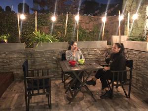 two women sitting at a table in a garden at night at Alfonsina Hostel in Buenos Aires