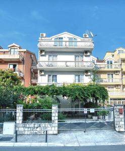 a tall white building with a fence in front of it at Sun Guest House in Budva