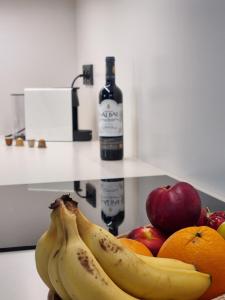 un bol de fruta con plátanos y manzanas y una botella de vino en Antiquari de Blanes Apartamento rústico modernizado en la Costa Brava en Blanes
