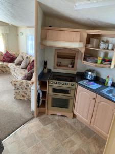 a kitchen with a stove and a couch in a room at Caravan 131 in Norwich