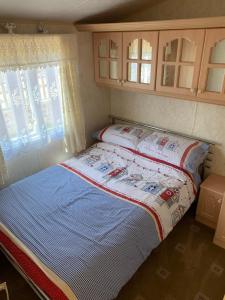 un piccolo letto in una piccola camera con finestre di Caravan 131 a Norwich
