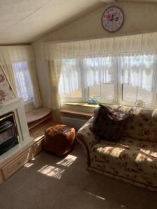 a living room with a couch and a clock on the wall at Caravan 131 in Norwich