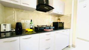 a kitchen with white cabinets and a black counter top at BluO Stylish 2BHK New Town Rajarhat - Skyline View Condo in Kolkata