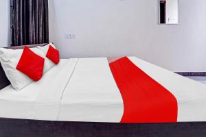 Una cama con dos almohadas rojas y blancas. en Super OYO Flagship Royal Residency en Nāmakkal