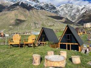 two chairs and a table in front of a house at Kazbegi Hills Cottages in Stepantsminda