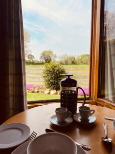 a table with two cups and a tea pot and a window at Keepers Lodges in Broadway