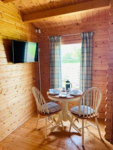 een eetkamer met een tafel en stoelen en een televisie bij Keepers Lodges in Broadway