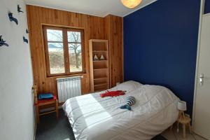 um quarto com uma cama branca e uma parede azul em Les Herbes Rouges chalet with panoramic view 