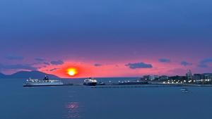 un coucher de soleil avec deux navires de croisière dans l'eau dans l'établissement Marina Premium Hotel, à Vlorë