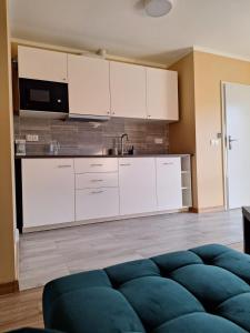 cocina con armarios blancos y sofá azul en Apartament 3A Świętoszewo 12 