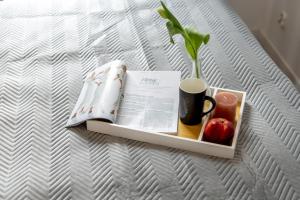 a tray with a book and a cup of coffee and an apple at Apartamenty Bałtyckie - Grand Baltic - WIFI, Klimatyzacja, Sala Zabaw, Taras wypoczynkowy, centrum Ustki in Ustka