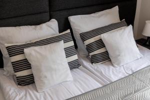 a white bed with four pillows on it at Apartamenty Bałtyckie - Grand Baltic - WIFI, Klimatyzacja, Sala Zabaw, Taras wypoczynkowy, centrum Ustki in Ustka