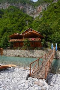 a wooden house on a river with a bridge at Eagles Land in Shkodër