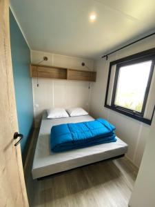 Ce lit se trouve dans une petite chambre dotée d'une fenêtre. dans l'établissement Camping Ostréa ****, à Dolus-d'Oléron