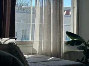 - une chambre dotée d'une fenêtre avec des rideaux et une plante dans l'établissement Joni Apartments, à Helsinki