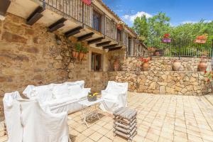 eine Terrasse mit weißen Stühlen und einer Steinmauer in der Unterkunft Villa Olmo With Private Pool in Castel di Lucio