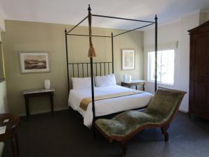 a bedroom with a four poster bed and a chair at Rosedene Guest House in Cape Town
