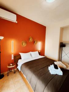 sypialnia z dużym łóżkiem z pomarańczową ścianą w obiekcie Poseidon Rooms w mieście Kala Nera
