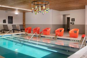 a swimming pool with orange chairs and a chandelier at Aloft by Marriott McAllen in McAllen