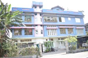 un edificio azul y blanco con una valla delante en Axom Aura, en Tezpur