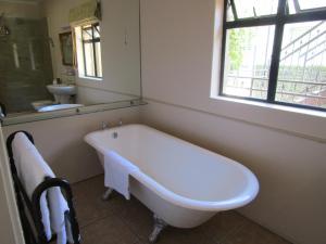La salle de bains est pourvue d'une baignoire blanche et d'une fenêtre. dans l'établissement Rosedene Guest House, au Cap
