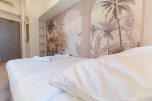 two beds in a room with palm trees on the wall at Hotel Le Céleste in Nice