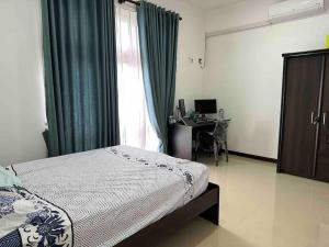a bedroom with a bed and a desk and a window at Beauty World Villa - Gampaha in Gampaha
