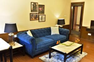 uma sala de estar com um sofá azul e duas mesas em Hotel Polo Towers Shillong em Shillong