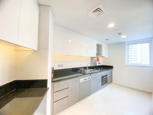 eine Küche mit weißen Schränken, einem Waschbecken und einem Fenster in der Unterkunft Comfy 1BR in Damac Maison Prive by Huaxia Homes in Dubai
