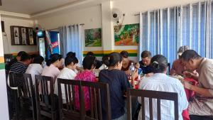un grupo de personas sentadas en una mesa comiendo comida en Hotel Kanthak, en Rummindei