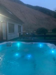 a swimming pool with blue lights in front of a house at Captivating 5-Bed Cottage with private hot tub in Spean Bridge