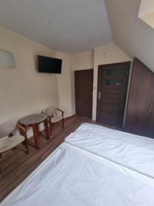 1 dormitorio con cama, mesa y TV en Pokoje gościnne "Mila" en Kąty Rybackie
