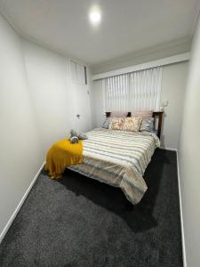 a bedroom with a large bed with a yellow blanket at Auckland airport holiday home in Auckland